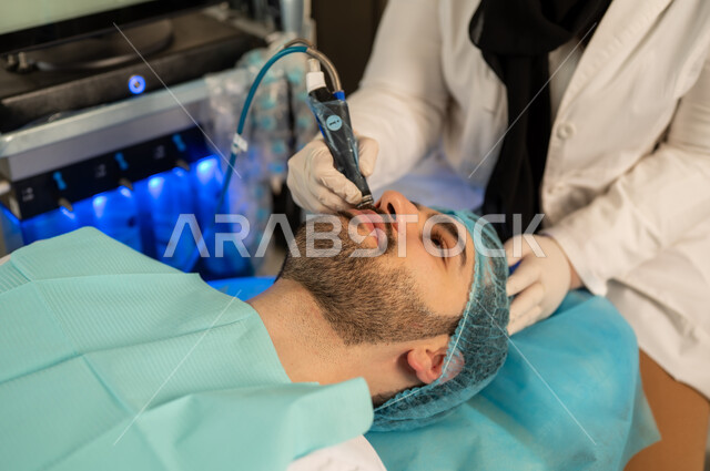 Using cosmetics, a handsome young Saudi Arabian Gulf man wearing traditional thobe, pore cleansing device, moisturizing and lightening the skin, a picture of a dermatologist using skin care devices, an Omani man on a treatment chair in a skin care clinic, the concept of skin freshness and improvement, concealing facial wrinkles, combating premature aging.