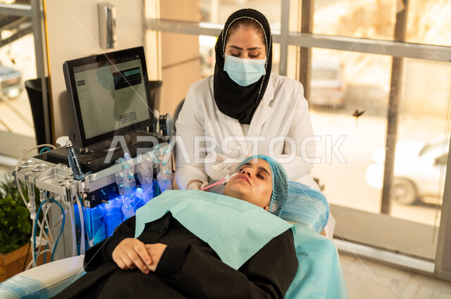 استخدام أدوات وفرشاة التجميل ، روتين العناية بالبشرة، خبيرة تجميل تقوم بوضع مواد وميك اب على وجه الزبونة، امرأة عربية خليجية سعودية في صالون تجميلي نسائي بايماءات الاسترخاء، الاهتمام بالجمال والمظهر الخارجي، امرأة عمانية تهتم بمفهوم الأنوثة والنعومة .