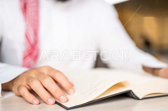 صورة مقربة لرجل عربي خليجي سعودي يقرا الكتاب، باحث علمي، كتاب جامعي، قصص وروايات، اكتساب المعرفة، تعليم وثقافة