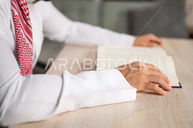 صورة مقربة لرجل عربي خليجي سعودي يقرا الكتاب، باحث علمي، كتاب جامعي، قصص وروايات، اكتساب المعرفة، تعليم وثقافة