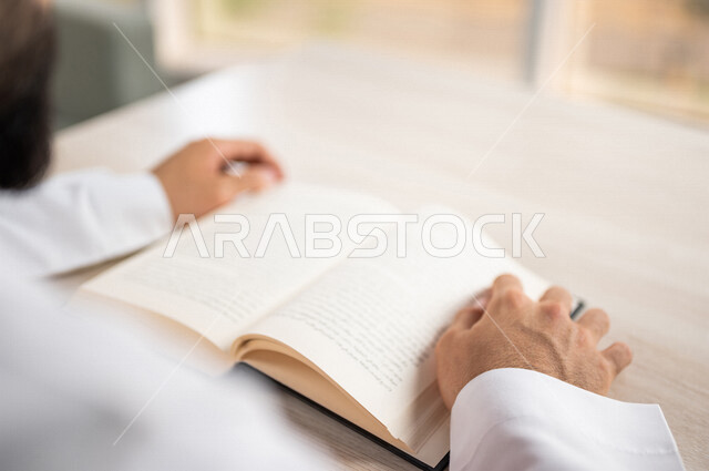 صورة مقربة لرجل عربي خليجي سعودي يقرا الكتاب، باحث علمي، كتاب جامعي، قصص وروايات، اكتساب المعرفة، تعليم وثقافة