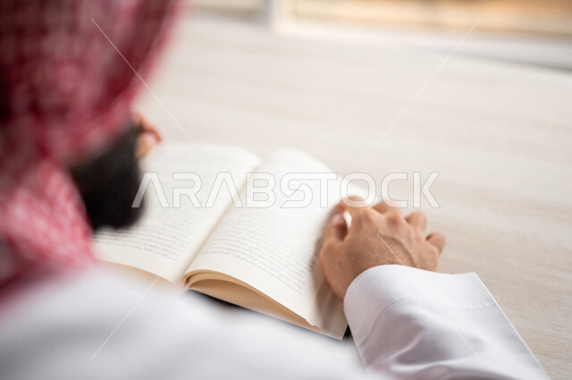 صورة مقربة لرجل عربي خليجي سعودي يقرا الكتاب، باحث علمي، كتاب جامعي، قصص وروايات، اكتساب المعرفة، تعليم وثقافة