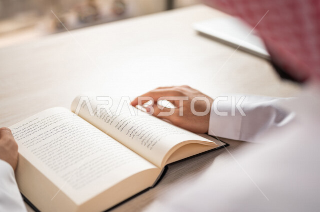 صورة مقربة لرجل عربي خليجي سعودي يقرا الكتاب، باحث علمي، كتاب جامعي، قصص وروايات، اكتساب المعرفة، تعليم وثقافة