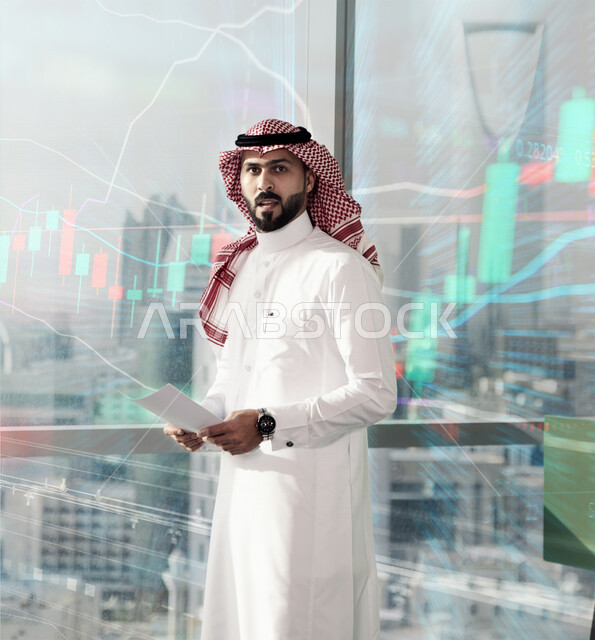 رجل اعمال عربي سعودي خليجي في مقر العمل, رسومات هولوجراميه توضح نسبة انجاز الاعمال, متابعة سوق الاسهم, الاقتصاد المالي, اعمال الكترونيه تجاريه, حسابات واحصاءات بيانيه باستخدام تقنية الهولوجرام ثلاثية الابعاد, ايماءات وجه تدل على الدهشه