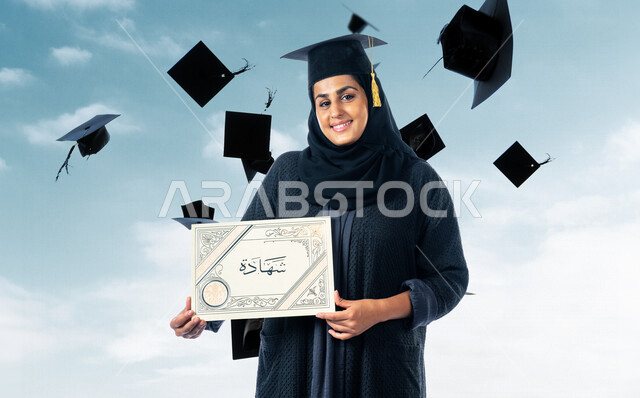 صورة لطالبة جامعية خريجة عربية سعودية خليجية تلبس قبعة التخرج و تحمل شهادة تخرجها , ايماءات وجه ويدين تدل على السعادة بالتفوق والنجاح, حفل تخرج, نتائج الاختبارات, تلميذه متفوقه, مدارس وجامعات, التعليم في المملكة العربية السعودية