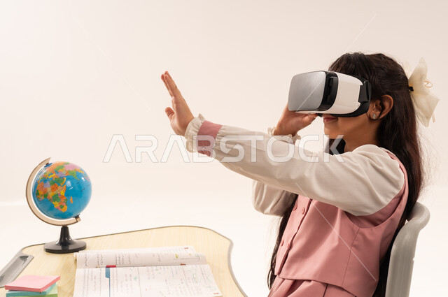 Following new educational methods, integrating modern technologies into academic life, a Saudi female student sitting at a study table, advanced academies and schools, a close-up side portrait of an Arab Gulf Omani female student wearing a school uniform enjoying watching through virtual reality glasses, white background