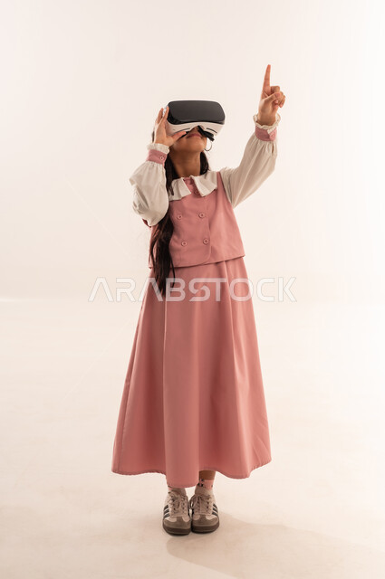 Smart education via virtual reality glasses, combining learning with entertainment using modern technology, advanced schools and academies, portrait of an Arab Gulf Omani student wearing a uniform and school bag, a Saudi student pointing at something, full body, white background