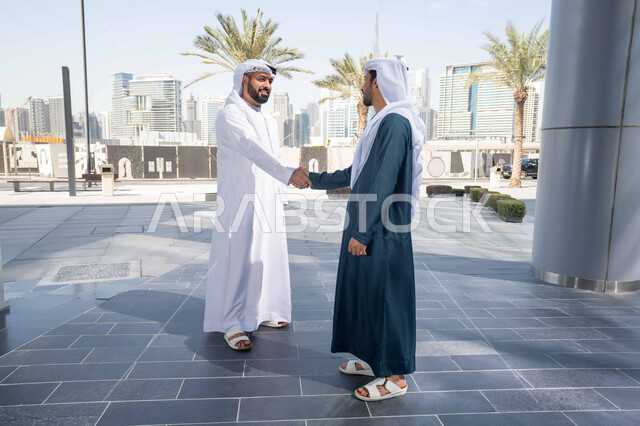 الوقوف بثقة في شوارع المدينة، قضاء أوقات ممتعة مع الاصدقاء ، صداقات وتعارف ونقاشات وحوارات ، رجلان عربيان خليجيان اماراتيان يتصافحان بحرارة، اجواء العيد، عادات العيد في المجتمع الاماراتي ، الاحتفال بالعيد السعيد، اعياد ومناسبات ، مفهوم الأناقة والاهتمام بالمظهر الخارجي .