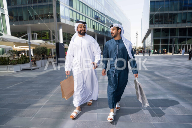 الاستفادة من العروض والتخفيضات التجارية ، قضاء أوقات ممتعة في الطبيعة ، التجول واستنشاق الهواء النقي في وقت النهار، صداقات وتعارف ونقاشات وحوارات ، صديقان عربيان خليجيان اماراتيان يرتديان الكندورة والغترة البيضاء ،  يحملان اكياس التسوق بتعابير السرور.