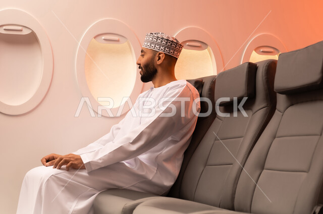 الجلوس بأدب وسكينه داخل الطائره, بورتريه مقرب من الجانب لرجل عربي خليجي عماني يرتدي الدشداشة والكمة يجلس على مقعد داخل الطائره السياحيه الخليجيه العمانيه منتظرا موعد وصول الطائره,  الطيران الخليجي العماني