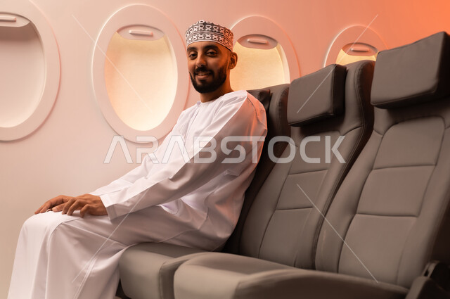 الجلوس بأدب وسكينه داخل الطائره, بورتريه مقرب من الجانب لرجل عربي خليجي عماني يرتدي الدشداشة والكمة يجلس على مقعد داخل الطائره السياحيه الخليجيه العمانيه منتظرا موعد وصول الطائره,  الطيران الخليجي العماني