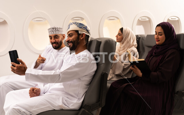 قضاء أوقات ممتعة داخل الطائرة ، بورتريه مقرب من الجانب لمسافرون من العرب العمانيون الخليجيون داخل مقصورة الطائرة يرتدون الزي العماني، ايماءات تدل على الفرح والسعادة ، رحلات سياحية جويه ممتعة، عطلة صيفية عائلية، الخطوط الجوية العمانيه، سياحة وسفر