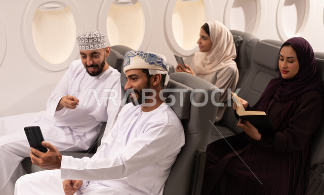 قضاء أوقات ممتعة داخل الطائرة ، بورتريه مقرب من الجانب لمسافرون من العرب العمانيون الخليجيون داخل مقصورة الطائرة يرتدون الزي العماني، ايماءات تدل على الفرح والسعادة ، رحلات سياحية جويه ممتعة، عطلة صيفية عائلية، الخطوط الجوية العمانيه، سياحة وسفر