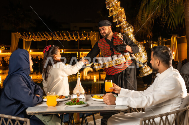 روح الكرم و المشاركه, الاحتفال بقدوم شهر الخير, الاستمتاع بالمشروبات التقليدية, بائع تمر هندي يصب الشراب , عائله عربيه خليجيه سعودية ترتدي الزي التقليدي تستمع بالاجواء الرمضانية , طفلة تقوم بتناول المشروب