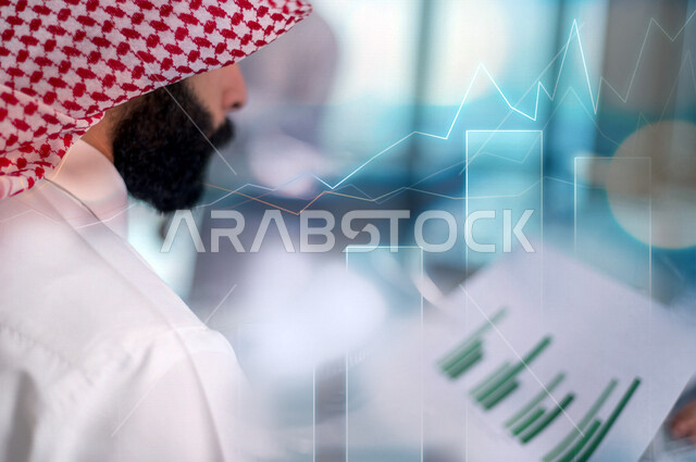 صورة لرجل عربي سعودي خليجي يحمل بيديه ورقة الرسوم البيانية التوضيحية , تملك العقارات , الإستثمار المالي , الإحصائيات والحسابات , القروض البنكية , خلفية الرسوم البيانية التوضيحية , صعود وانهيار العقار .