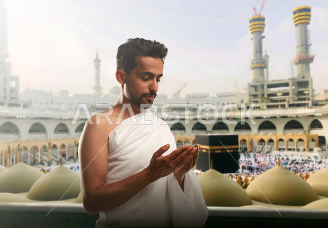 أداء مناسك الحج و العمرة, أماكن و معالم دينة إسلامية مقدسة في المملكة العربية السعودية, العبادة و التقرب إلى الله, رجل عربي خليجي سعودي يرتدي ملابس الاحرام يقف امام الكعبه الشريفه يقوم بالدعاء