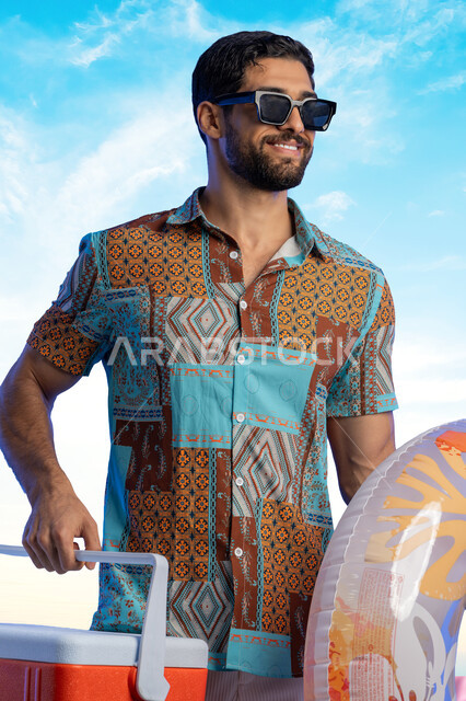 Preparing for a fun summer vacation, the concept of relaxation and tranquility, chalets, hotels and luxury tourist resorts in the Kingdom of Saudi Arabia, a Saudi Arabian Gulf man wearing casual clothes and sunglasses carrying a drink holder and a float in his hand