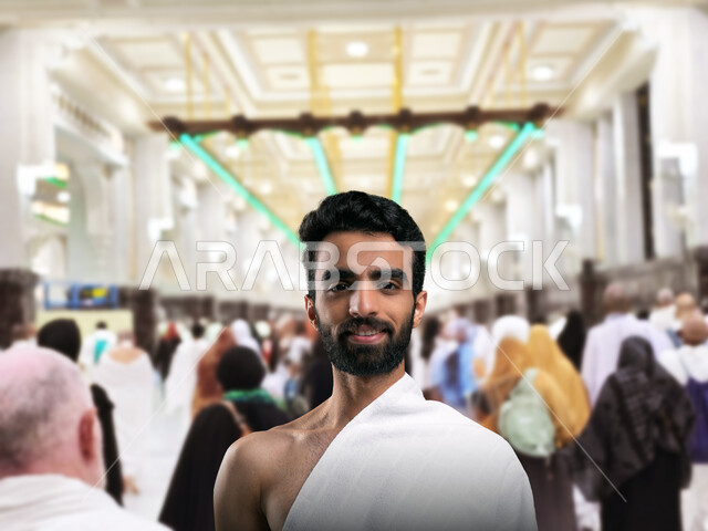 مفهوم العبادة والتقرب الى الله, اداء مناسك الحج و العمرة, أماكن و معالم دينة إسلامية مقدسة في المملكة العربية السعودية, صورة مقربة لرجل عربي خليجي سعودي يرتدي ملابس الاحرام يقف مبتسما امام الصفا والمروه