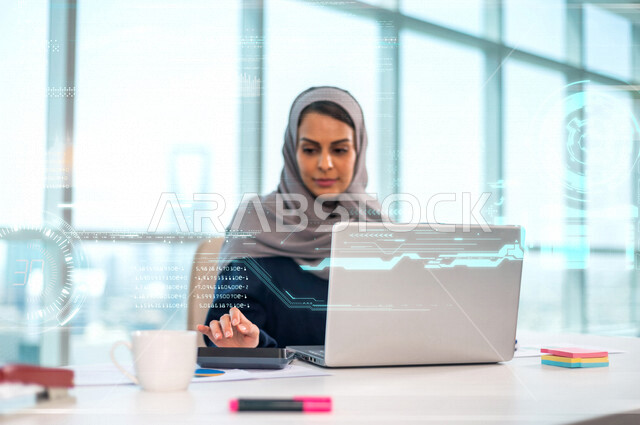 سيدة عربية خليجية سعودية تجلس امام الحاسوب المحمول وتستخدم الالة الحاسبة ، موظفة تعمل في مجال المحاسبة ،اعداد القوائم المالية وحساب التدفقات النقدية ، ادارة حسابات الشركة