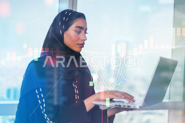 سيدة عربية خليجية سعودية تستخدم الحاسوب المحمول ، تراقب  صعود و نزول البورصة المالية ، الاستثمار المالي و الاقتصادي ، التطور الإقتصادي ، خلفية رسومات بيانية ثلاثية الأبعاد بتقنية الهولوجرام