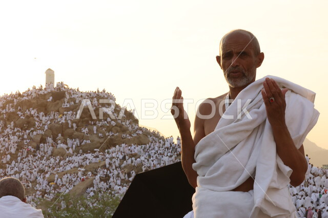 حاج يرتدي لباس الاحرام يقف على جبل عرفات، مفهوم العبادة والتقرب إلى الله، الحجاج والمعتمرين في مكة المكرمة، آدء مناسك الحج في يوم عرفة, مقصد المسلمين من أنحاء العالم, مكان ومعلم إسلامي ديني مقدس في المملكة العربية السعودية، موسم الحج 2025