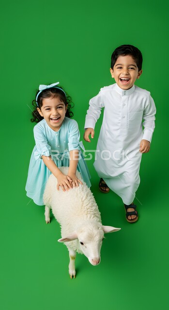 قربان واضحية عيد الأضحى المبارك، الاحتفال بالمناسبات والأعياد الدينية الإسلامية، بورتريه لولد عربي خليجي سعودي مبتسم يرتدي الثوب التقليدي يقف مع اخته بجانب خاروف أبيض لطيف،  خلفية خضراء