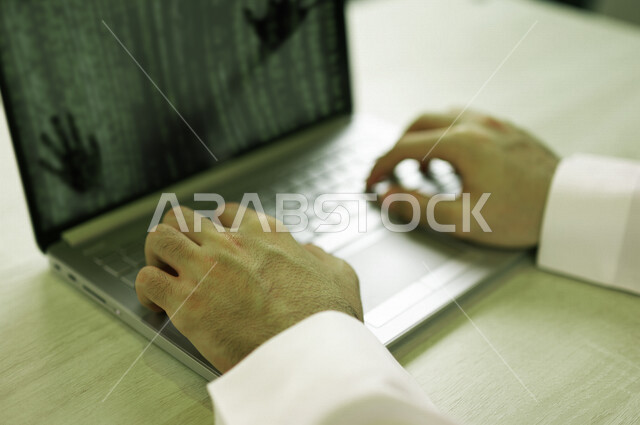 رجل عربي خليجي سعودي يستخدم الحاسوب المحمول ،يعمل على اختراق حماية وأمن وبيانات المستخدمين، استخدم جهاز الحاسوب في الهجمات السيبرانية، الجرائم الالكترونية