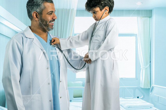 طفل عربي خليجي سعودي يستخدم سماعة الطبيب لاجراء الفحص الطبي ،مهنة مستقبلية ، مفهوم الطب والرعاية الصحية ، تقديم الرعاية والفحص الطبي ، مهن ووظائف طبية ، خلفية غرفة الطبيب