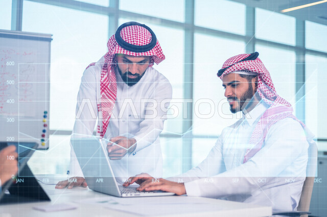 موظفان عربيان خليجيان سعوديان يستخدمان الحاسوب المحمول، متابعة صعود ونزول البورصة عبر الانترنت ، الاستثمار والتداول في البورصة ، الاقتصاد والنمو المالي ، مفهوم التحليل المالي وفرص الاستثمار ، خلفية المخطط البياني بتقنية الهولوجرام
