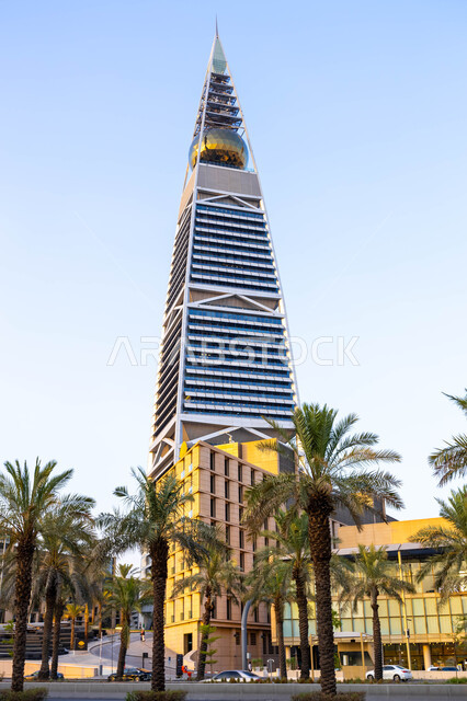 برج الفيصلية في العاصمة الرياض في النهار، التطور والتقدم العمراني للمنشأت في المملكة العربية السعودية، التصاميم الهندسية المعمارية على الطراز الحديث والمتطور، منظر السماء الزرقاء الصافية، مكان سياحي مشهور، الفن الهندسي للابراج وناطحات السحاب