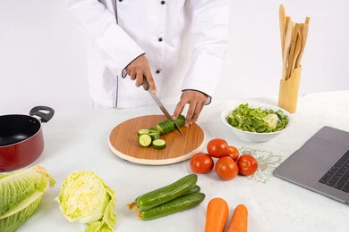 حب التدرب على مهارة الطهي وإعداد الطعام، احترافية تقطيع الخضار، بورتريه مقرب لرجل عربي خليجي اماراتي يرتدي زي العمل يحضر طبق صحي مفيد، شيف سعودي يقوم بتحضير سلطة الخضراوات الطازجة، استخدام المكونات والمقادير المناسبة للوجبة، خلفية بيضاء