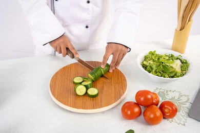 طباخ يتقن مهارة الطهي وإعداد الطعام، احترافية تقطيع الخضار، بورتريه مقرب لأيدي رجل عربي خليجي اماراتي يرتدي زي العمل يحضر طبق صحي مفيد، شيف سعودي يقوم بتحضير سلطة الخضراوات الطازجة، استخدام المكونات والمقادير المناسبة للوجبة، خلفية بيضاء