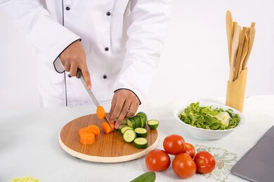 احترافية تقطيع الخضار، شغف التدرب على مهارة الطهي وإعداد الطعام، بورتريه مقرب لرجل عربي خليجي اماراتي يرتدي زي العمل يحضر طبق صحي مفيد، شيف سعودي يقوم بتحضير سلطة الخضراوات الطازجة، استخدام المكونات والمقادير المناسبة للوجبة، خلفية بيضاء