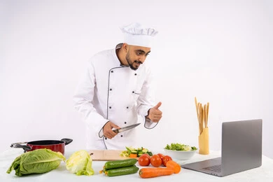 رفع اصبع الابهام للأعلى بإيماءات الإعجاب، تعلم فنون الطهي من خلال المواقع الإلكترونية عبر الحاسوب، توعية المجتمع بإعداد الطعام الصحي، بورتريه لرجل عربي خليجي اماراتي يرتدي زي العمل يقوم بتصوير وعرض الطبخ عبر اللابتوب، شيف سعودي يحضر وصفة عبر بث مباشر، خلفية بيضاء