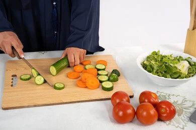 أهمية الطعام الصحي، إعداد السلطات والاطباق الصحية، اتباع نظام غذائي صحي، شغف تعلم مهارة الطهي، بورتريه مقرب لسيدة عربية خليجية اماراتية ترتدي عباءة تقوم بتحضير طبق مفيد، ربة منزل سعودية تقوم بتقطيع الخضراوات الطازجة، خلفية بيضاء