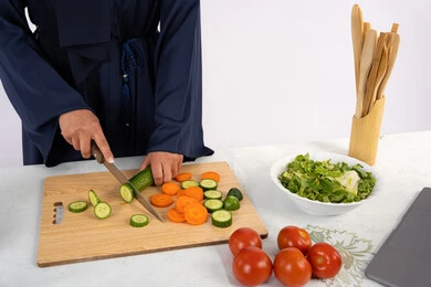 اطباق وسلطات صحية من الخضراوات الطازجة، اتباع نظام غذائي صحي، شغف تعلم مهارة الطهي، بورتريه مقرب لسيدة عربية خليجية اماراتية ترتدي عباءة تقوم بتحضير طبق مفيد، ربة منزل سعودية تقوم بتقطيع الخضراوات الطازجة، خلفية بيضاء