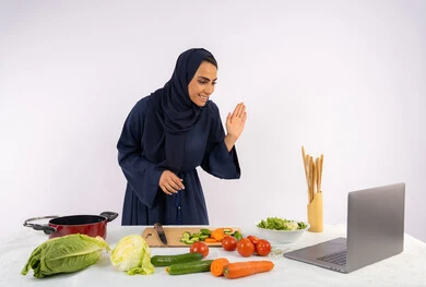 ايماءات إلقاء التحية والسلام، تعلم وتطبيق فنون الطهي من خلال المواقع الإلكترونية، إعداد الطعام الصحي، بورتريه لامرأة عربية خليجية اماراتية محجبة ترتدي العباءة تقوم بتصوير وعرض الطبخ عبر اللابتوب، ربة منزل سعودية تشرح المكونات والكميات المطلوبة عبر بث مباشر، خلفية بيضاء