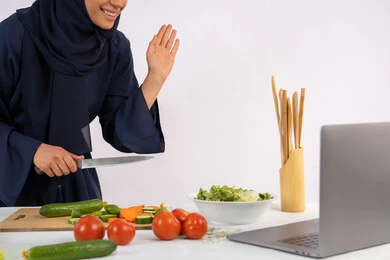 إلقاء التحية والسلام، تعلم وتطبيق فنون الطهي من خلال المواقع الإلكترونية، إعداد الطعام الصحي، بورتريه لامرأة عربية خليجية اماراتية محجبة ترتدي العباءة تقوم بتصوير وعرض الطبخ عبر اللابتوب، ربة منزل سعودية تشرح المكونات والكميات المطلوبة عبر بث مباشر، خلفية بيضاء