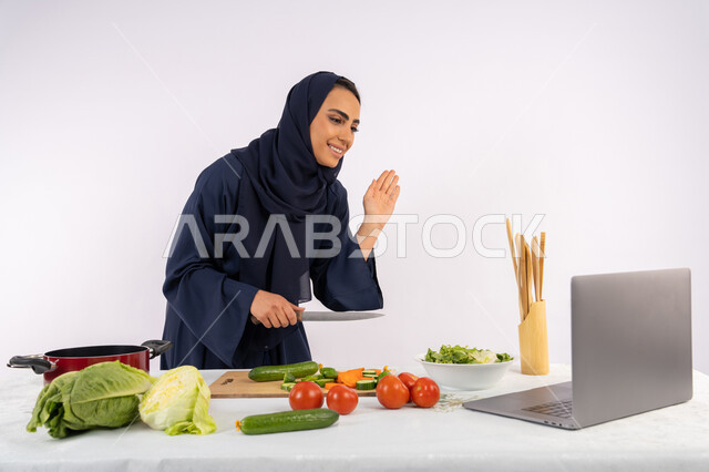 إعداد الطعام الصحي، إلقاء التحية والسلام، تعلم وتطبيق فنون الطهي من خلال المواقع الإلكترونية، بورتريه لامرأة عربية خليجية اماراتية محجبة ترتدي العباءة تقوم بتصوير وعرض الطبخ عبر اللابتوب، ربة منزل سعودية تشرح المكونات والكميات المطلوبة عبر بث مباشر، خلفية بيضاء