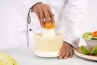 شيف سعودي يقوم بتحضير عصير مفيد، شغف تعلم مهارة الطهي، مفهوم النظام الغذائي الصحي، اعداد المشروبات الصحية والطازجة، بورتريه مقرب لرجل عربي خليجي اماراتي يرتدي زي الطهاة يعصر البرتقال الطازج، خلفية بيضاء