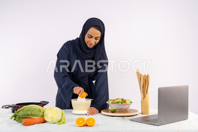 مشاركة الوصفة عبر مواقع التواصل الاجتماعي، اعداد المشروبات الصحية والطازجة، اتباع نظام غذائي صحي، تعلم مهارة الطهي باستخدام الحاسوب، بورتريه لسيدة عربية خليجية اماراتية محجبة ترتدي عباءة تقوم بعصر البرتقال، ربة منزل سعودية تقوم بتحضير طبق مفيد، خلفية بيضاء