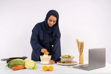 مشاركة الوصفة عبر مواقع التواصل الاجتماعي، اعداد المشروبات الصحية والطازجة، اتباع نظام غذائي صحي، تعلم مهارة الطهي باستخدام الحاسوب، بورتريه لسيدة عربية خليجية اماراتية محجبة ترتدي عباءة تقوم بعصر البرتقال، ربة منزل سعودية تقوم بتحضير طبق مفيد، خلفية بيضاء