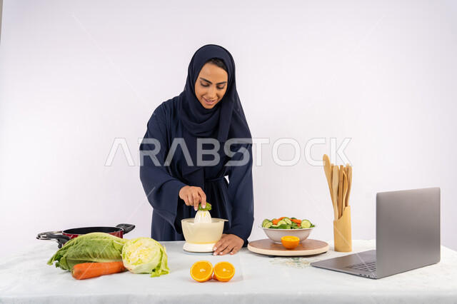 المشروبات الصحية والمنعشة، اتباع نظام غذائي صحي، تعلم مهارة الطهي باستخدام الحاسوب، بورتريه لسيدة عربية خليجية اماراتية محجبة ترتدي عباءة تقوم بعصر الليمون، ربة منزل سعودية تقوم بتحضير طبق مفيد، مشاركة الوصفة عبر مواقع التواصل الاجتماعي، خلفية بيضاء