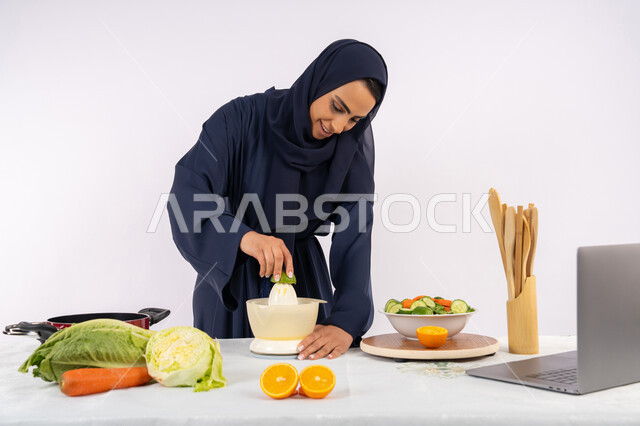 اعداد المشروبات الصحية، اتباع نظام غذائي صحي، تعلم مهارة الطهي باستخدام الحاسوب، بورتريه لسيدة عربية خليجية اماراتية محجبة ترتدي عباءة تقوم بعصر الليمون، ربة منزل سعودية تقوم بتحضير طبق مفيد، مشاركة الوصفة عبر مواقع التواصل الاجتماعي، خلفية بيضاء