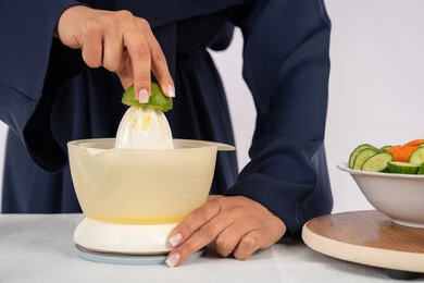 Saudi housewife preparing healthy juice, concept of healthy diet, love to learn cooking skill, preparing healthy and fresh drinks, close-up portrait of an Arab Gulf Emirati woman wearing an abaya squeezing fresh oranges, white background
