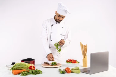 احترافية اختيار الخضار، مشاركة الوصفات على مواقع الانترنت عبر الحاسوب المحمول، شيف سعودي يقوم بتحضير سلطة الخضراوات الطازجة، شغف التدرب على مهارة الطهي وإعداد الطعام، بورتريه لرجل عربي خليجي اماراتي يرتدي زي العمل يحضر طبق صحي مفيد، خلفية بيضاء