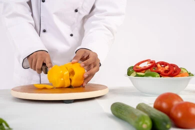 احترافية تقطيع الخضار، شغف التدرب على مهارة الطهي وإعداد الطعام، بورتريه مقرب لرجل عربي خليجي اماراتي يرتدي زي العمل يحضر طبق صحي مفيد، شيف سعودي يقوم بتحضير سلطة الخضراوات الطازجة، استخدام المكونات والمقادير المناسبة للوجبة، خلفية بيضاء