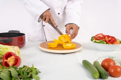 فنون تقطيع الخضار، شغف التدرب على مهارة الطهي وإعداد الطعام، بورتريه مقرب لرجل عربي خليجي اماراتي يرتدي زي العمل يحضر طبق صحي مفيد، شيف سعودي يقوم بتحضير سلطة الخضراوات الطازجة، استخدام المكونات والمقادير المناسبة للوجبة، خلفية بيضاء