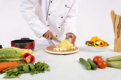 Professionalism in cutting vegetables, passion for practicing cooking and food preparation skills, close-up portrait of an Emirati Gulf Arab man in business attire preparing a healthy and useful dish, Saudi chef preparing fresh vegetable salad, using appropriate ingredients and quantities for the meal, white background