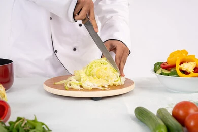 طريقة تقطيع الخضار باحترافية، شغف التدرب على مهارة الطهي وإعداد الطعام، بورتريه مقرب لرجل عربي خليجي اماراتي يرتدي زي العمل يحضر طبق صحي مفيد، شيف سعودي يقوم بتحضير سلطة الخضراوات الطازجة، استخدام المكونات والمقادير المناسبة للوجبة، خلفية بيضاء